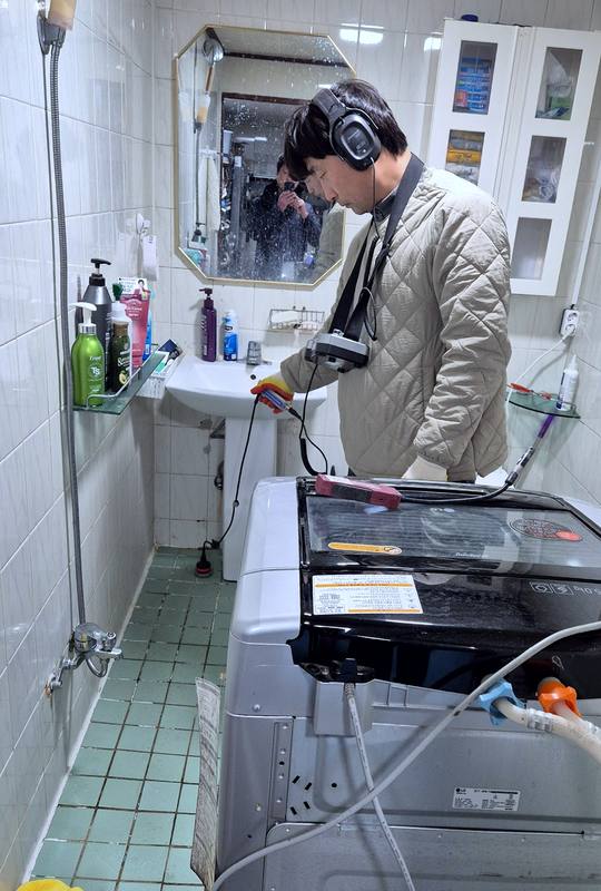 화성 누수탐지 — 욕실에서 헤드셋을 쓰고 청음 장비로 배관 소리를 확인하는 기술자